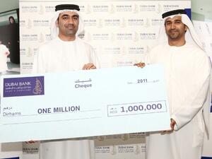 Waleed Al Awadi handing the Kunooz winner's cheque to winner Eisa Al Hammadi