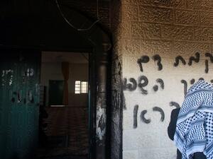 A Palestinian man looks at graffiti scrawled at the entrance to a mosque that reads in Hebrew, "Arabs out" and "Revenge for blood spilled in Qusra" in the West Bank village of Deir Istiya which lies next to the Israeli settlement of Ariel on Tuesday.
