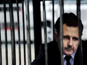 متظاهر يضع قناعا يمثل الرئيس السوري بشار الاسد ويجلس ارضا في قفص امام المحكمة الجنائية الدولية في لاهاي
