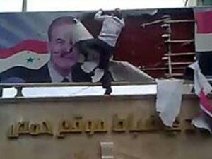 سوري يمزق صورة الاسد ووالده 