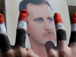 مؤيد للرئيس السوري يرفع شارة النصر امام صورته 