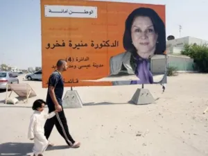 بحريني يسير مع ابنه امام ملصق انتخابي لمرشحة في البحرين
