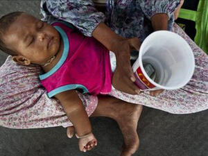 The reality of a tired baby on the lap of a beggar is harsh and depressing. (AP)