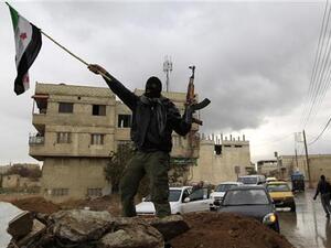 جندي سوري منشق يلوح بعلم المعارضة السورية في دمشق
