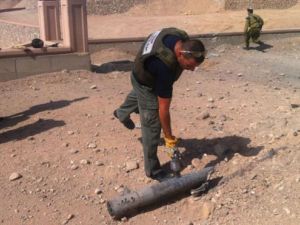 An Eilat policeman picks up a piece of one of the rockets (Courtesy of Haaretz/Eilat Police)