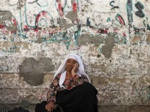 امرأة فلسطينية تجلس على الارض أمام منزلها في خان يونس بقطاع غزة
