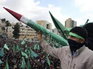 شاب فلسطيني يرفع نموذجا لصاروخ تصنعه حركة حماس خلال المسيرة في الخليل
