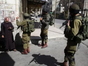 جنود اسرائيليون يوقفون سيدة فلسطينية في الجزء الفلسطيني من مدينة الخليل

