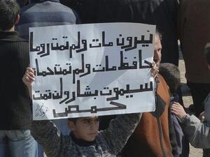 صبي يرفع لافتة تندد بالاسد في بلدة الحولة قرب حمص 
