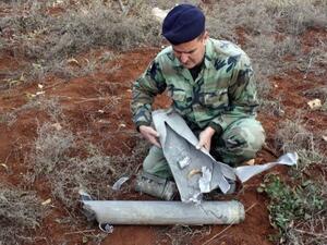 A Lebanese soldier examines one of the shells fired into his country's southern territory from Israel Sunday (Ali Dia/AFP)