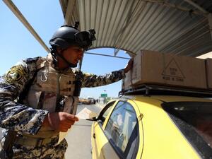 A member of the Iraqi interior ministry's security forces stops a taxi cab for inspection at a checkpoint in Baghdad on August 27, 2013. (AFP)