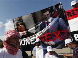 معارض سوري يحمل صورة للقذافي والاسد خلال احتجاج بوسط اسطنبول
