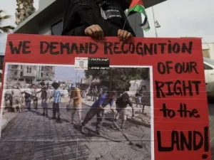 متظاهر يحمل لافتة تطالب بالاعتراف بحق الفلسطينيين في الارض