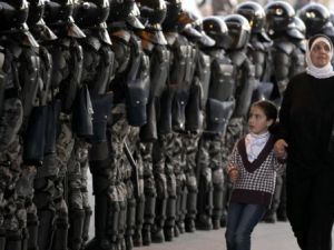 امراة وطفلة تمران من امام طابور لقوات الامن في الاردن