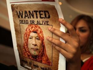 سيدة تقرأ صحيفة عروس البحر وعليها صورة تسخر من القذافي 