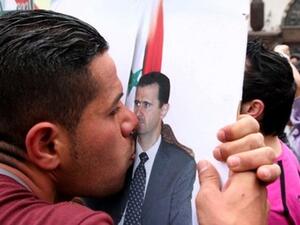 متظاهر من الموالين للاسد يقبل صورته في دمشق