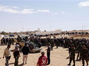 جنود من الجيش التونسي وسكان ولاجئين ليبيين بالقرب من سيارة مقلوبة تابعة للقوات القذافي بالقرب من الذهيبة 
