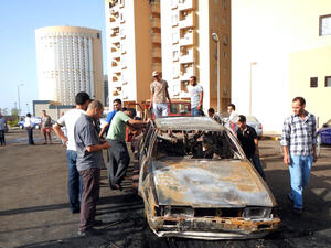 Men examine a car destroyed in a blast near embassies in Tripoli (AFP / MAHMUD TURKIA)