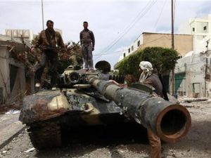 ثوار يقفون فوق دبابة مدمرة في مصراتة
