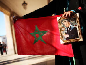 A woman holds a Moroccan flag and a portrait of King Mohammed VI at a protest in 2011. (Source: Spencer Platt / Getty)