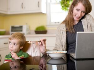Mothers are often expected to be the best multi-taskers: but here the mother might miss the child's mouth altogether as she juggles work and feeding.
