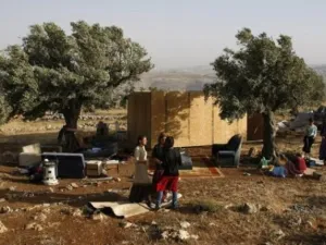 مستوطنون يقفون الى جانب كوخ من الخشب اعيد بناؤه في مستوطنة ميغرون العشوائية في الضفة الغربية 
