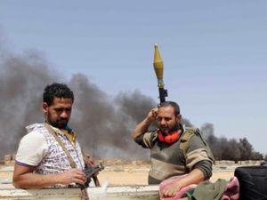 اعمدة دخان ترتفع خلف مقاتلين من الثوار في موقع يبعد نحو 130 كلم شرق سرت