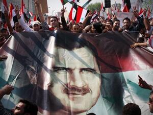 مؤيدون للاسد يشيرون بعلامة النصر خلال تظاهرة في ساحة امية في العاصمة دمشق