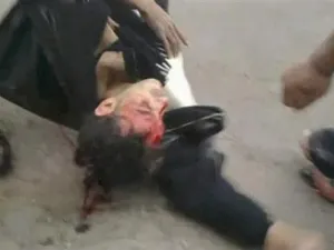 محتج ينزف من جروح في رأسه بعد أن تركه رفاقه على الارض في دمشق للاحتماء من اطلاق النار 
