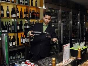 A bartender pours wine into a wine glass.