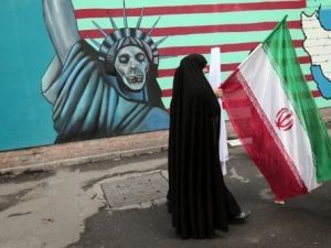 ايرانية تحمل علما وطنيا وتمر امام رسم مندد بالولايات المتحدة على جدار السفارة الاميركية السابق في طهران 
