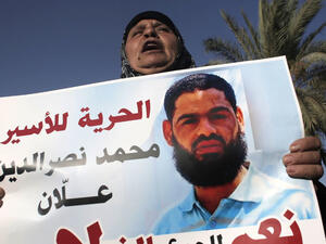 Maazouze, the mother of Muhammad Allan, a Palestinian prisoner who is on a long-term hunger strike, holds a portrait of her son during a rally calling for his release in the southern Israeli city of Beersheva on August 9, 2015. (AFP/Ahmad Gharabli)