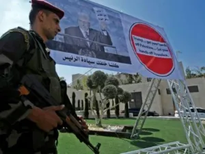 رجل أمن فلسطيني أمام ملصق للرئيس محمود عباس خلال تظاهرة ضد قرار واشنطن وقف مساعدتها لوكالة الانروا في بيت لحم

