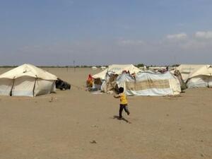 طفل يمني يركض في اتجاه خيمة داخل مخيم للنازحين في في منطقة الحديدة
