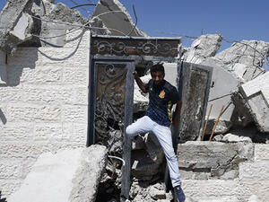 A Palestinian man exists through the door of a house, that was demolished by Israeli army bulldozers, in the village of Qalandia, next to Israel's controversial separation barrier, between the Israeli occupied West Bank town of Ramallah. (AFP/File)