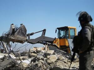 An Israeli soldier stands as a bulldozer pulls down the house of a Palestinian family near the West Bank town of Hebron. (AFP/Hazem Bader)