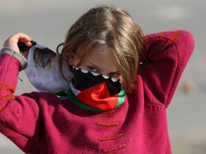 A Palestinian girl wraps a scarf around her face to protect from tear gas. (AFP/File)