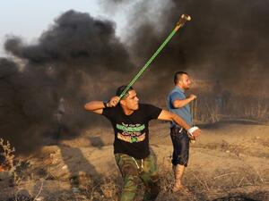 A Palestinian protester hurls a stone toward Israeli troops during clashes near a border fence between Israel and the Gaza Strip on Oct. 14, 2015 east of Bureij in central Gaza. (AFP/Mahmud Hams)