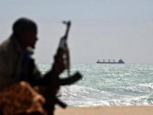 A pirate sits on the shore of a Nigerian beach, watching a ship. (AFP/Mohamed Dahir)