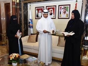 Ahmed Mahboob leafs through one of the books that will be distributed during the campaign, assisted by Sheikha al-Ghaferi and Sheikha Masoud