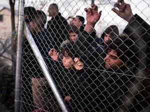 Refugees look through a fence towards the Macedonian side at the Greek-Macedonian border near the village of Idomeni on March 1 , 2016, where thousands are stranded. (AFP/Louisa Gouliamaki)