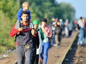 Refugees walk along the railway tracks on the Hugary-Serbia border on Sept. 14, 2015. (AFP/File)