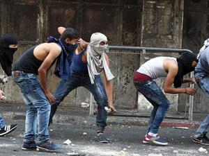 Palestinian youths throw stones towards Israeli security forces during clashes in the West Bank town of Hebron on October 4, 2015. (AFP/File)