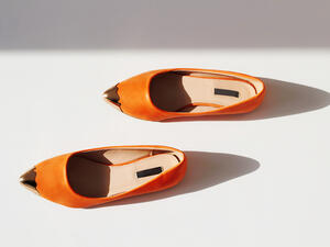 تتناغم الأحذية ذات اللون البرتقالي مع الجينز الأزرق بصفة خاصة، وكذلك مع الفساتين البيضاء (shutterstock.com)
