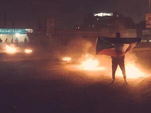 شاب سوداني يرفع علم بلاده خلال التظاهرات ضد الأوضاع الاقتصادية
