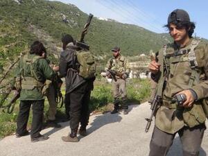 Rebel fighters gather along the road carrying their weapons near the village of Qasab and the border crossing with Turkey, in the northwestern province of Latakia, Syria, on March 23, 2014. (AFP/Amr Radwan Al-Homsi)