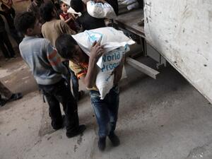 A Syrian child carries a sack of wheat, provided by the World Food Programme (WFP), in Kafr Batna, in the Eastern Ghouta area, on the outskirts of the capital Damascus on March 1, 2016. (AFP/Amer Almohibany)