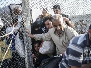 Syrians fleeing the war pass through border fences to enter Turkish territory illegally, near the Turkish border crossing at Akcakale in Sanliurfa province on June 14, 2015. (AFP/Bulent Kilic)