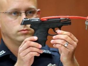 ضابط شرطة يمسك بالمسدس الذي استخدمه جورج زيمرمان في قتل المراهق تريفون مارتن
