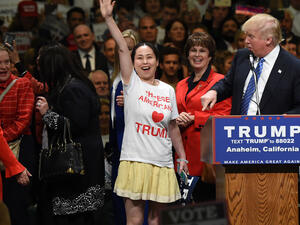 A supporter wearing a “Chinese Americans Love Trump” shirt takes the stage with other female Trump supporters at a campaign rally. (AFP/ ROBYN BECK)